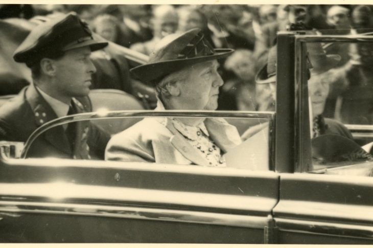 Intocht van koningin Wilhelmina met een rijtoer op op 6 juli 1945. Achter haar Erik Hazelhoff Roelfzema, haar adjudant. Afbeelding Haags Gemeentearchief